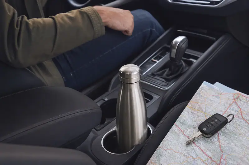 Bouteille en acier inoxydable placée dans le porte-gobelet de la console centrale d’une voiture