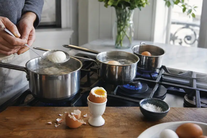 Une personne prépare des œufs dans des casseroles sur une cuisinière à gaz