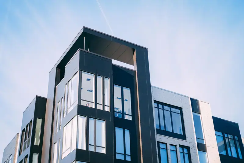 Immeuble moderne aux façades blanches et noires, avec grandes fenêtres sous un ciel bleu