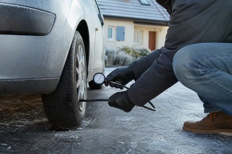 Une personne mesure la pression d’un pneu de voiture sur une chaussée gelée
