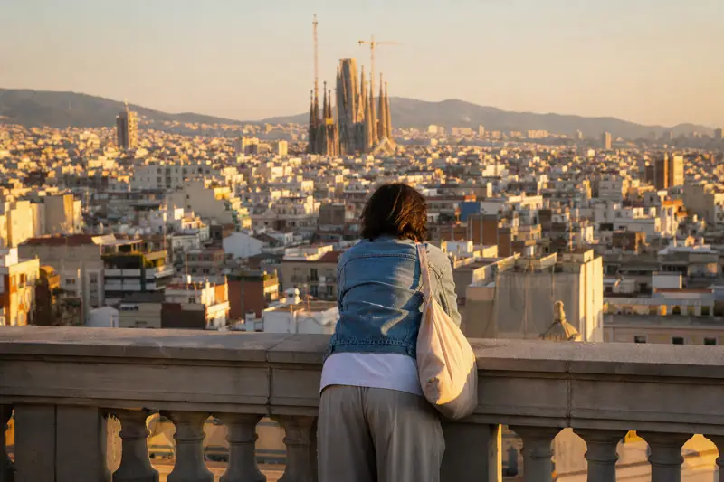 Une personne appuyée à une balustrade observe une ville dense dominée par une haute basilique